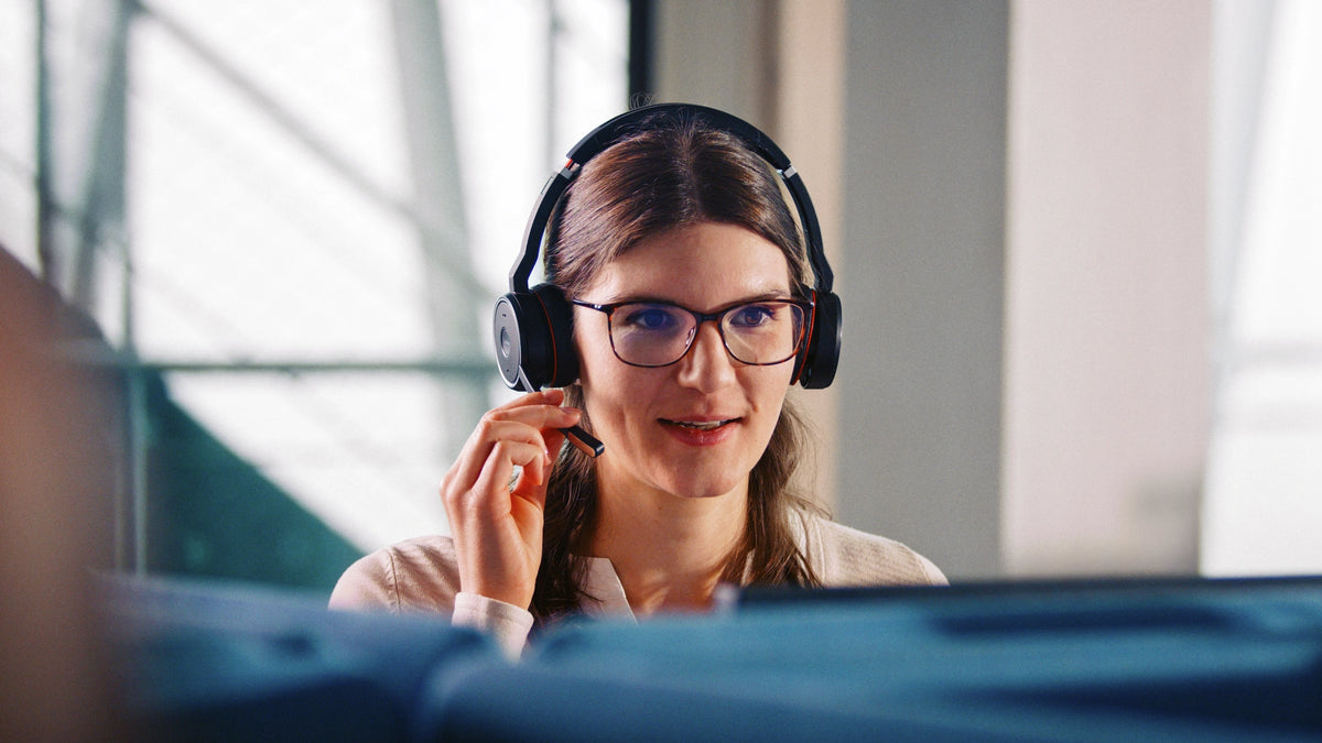 Woman wearing a headset and glasses, engaged in a conversation.