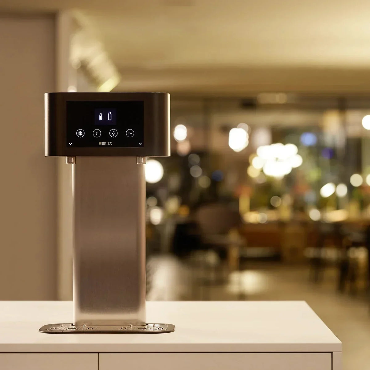 BRITA water dispenser on a countertop with a blurred, warmly lit interior in the background