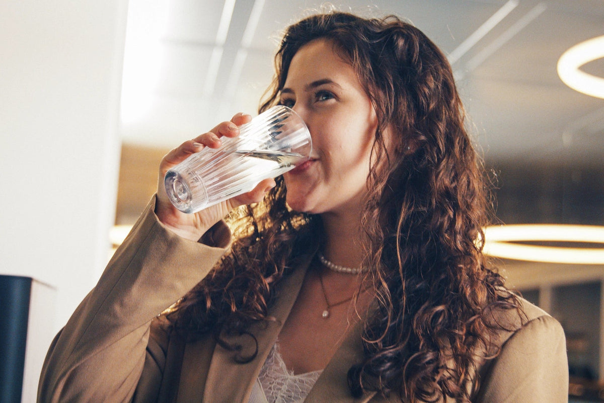 Woman drinking water with a blurred office background