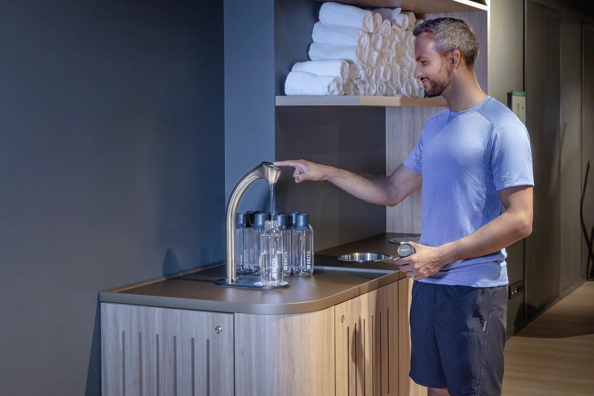 Man using a BRITA C-Tap in a gym environment.