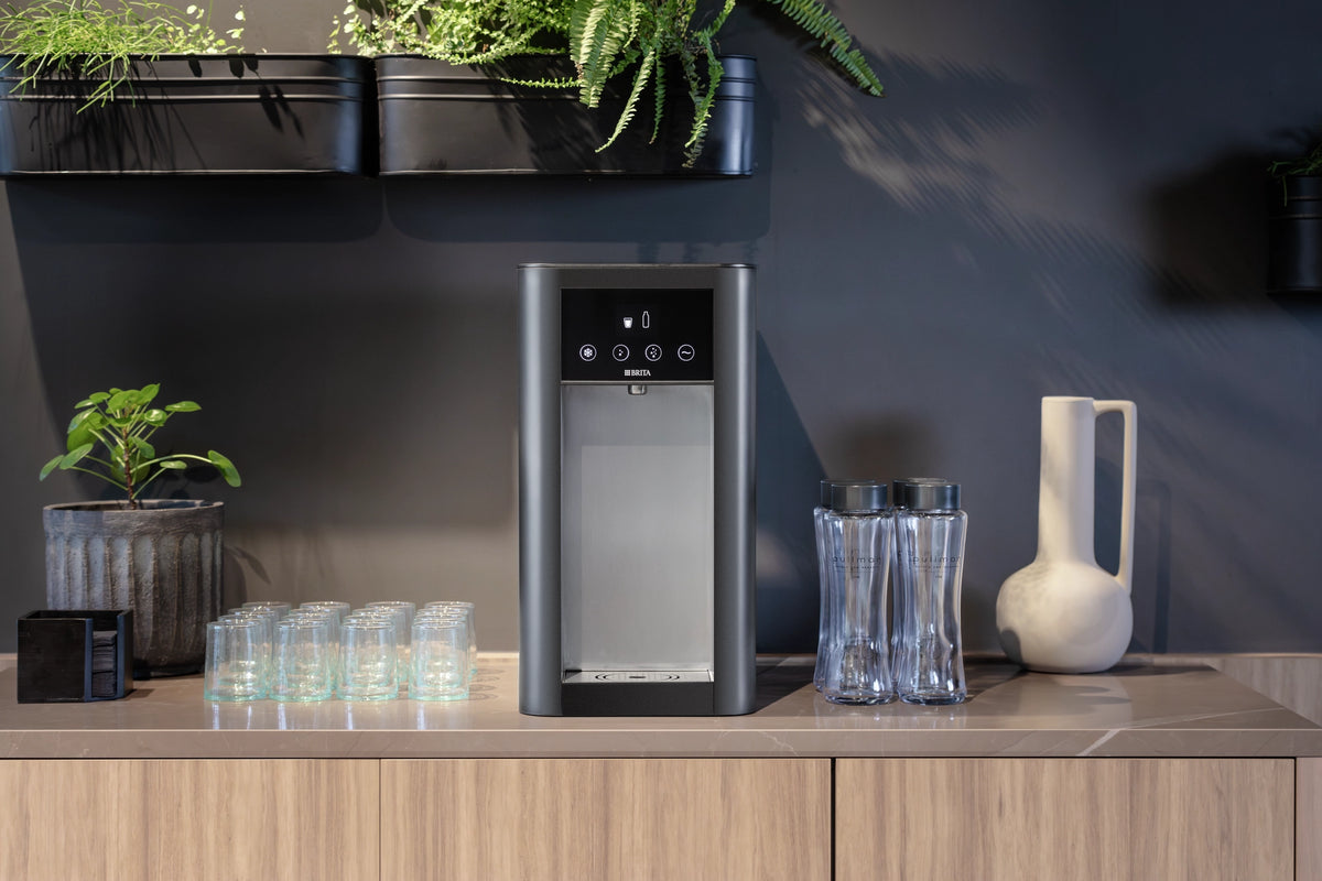 Modern kitchen setup with a Top Pro water dispenser, Twist bottles and glasses on the counter.